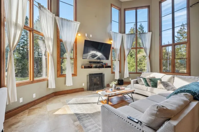 a living room with furniture a fireplace and a floor to ceiling window