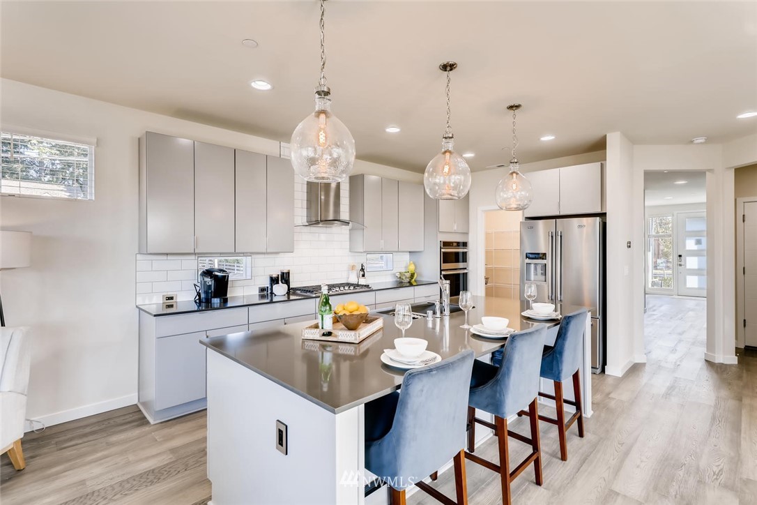4427 232nd Place Southeast, Unit 20 Bothell, WA 98021 - Photo 11 of 28 a kitchen with kitchen island a sink a stove a refrigerator and chairs