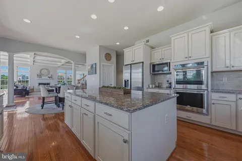 a dining room with stainless steel appliances a dining table wooden floor and a kitchen view
