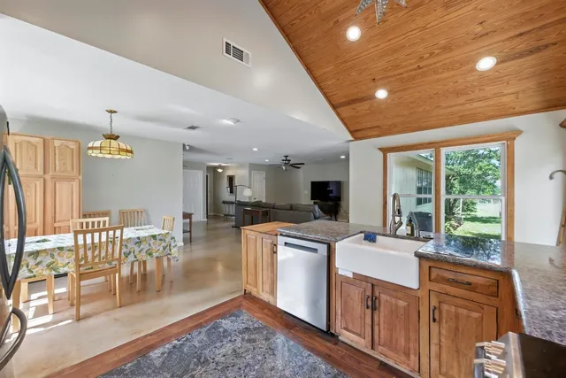 a view of a kitchen with kitchen island granite countertop a large window a sink and a counter top space
