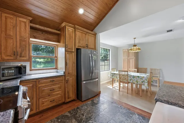 a kitchen with granite countertop a refrigerator a stove a dining table and chairs