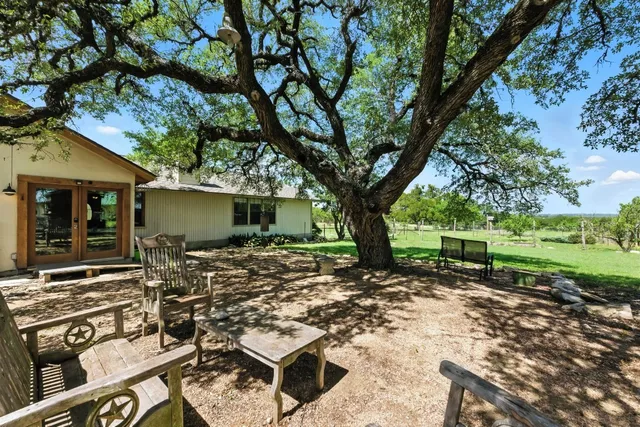 a view of a backyard with table and chairs under a large tree