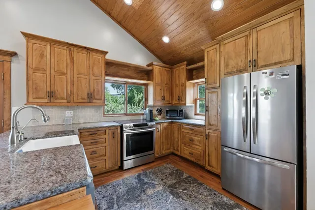 a kitchen with stainless steel appliances granite countertop a refrigerator sink and stove