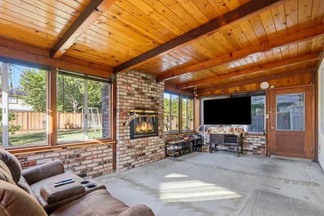 a living room with furniture a flat screen tv and floor to ceiling window