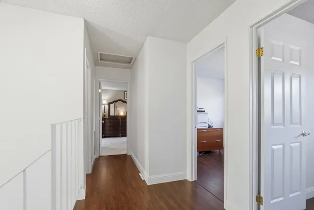 a view of a hallway with wooden floor and a bedroom