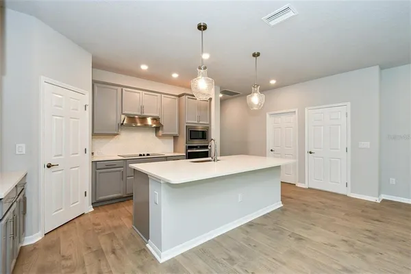 a large white kitchen with a stove a sink dishwasher and a refrigerator with wooden floor