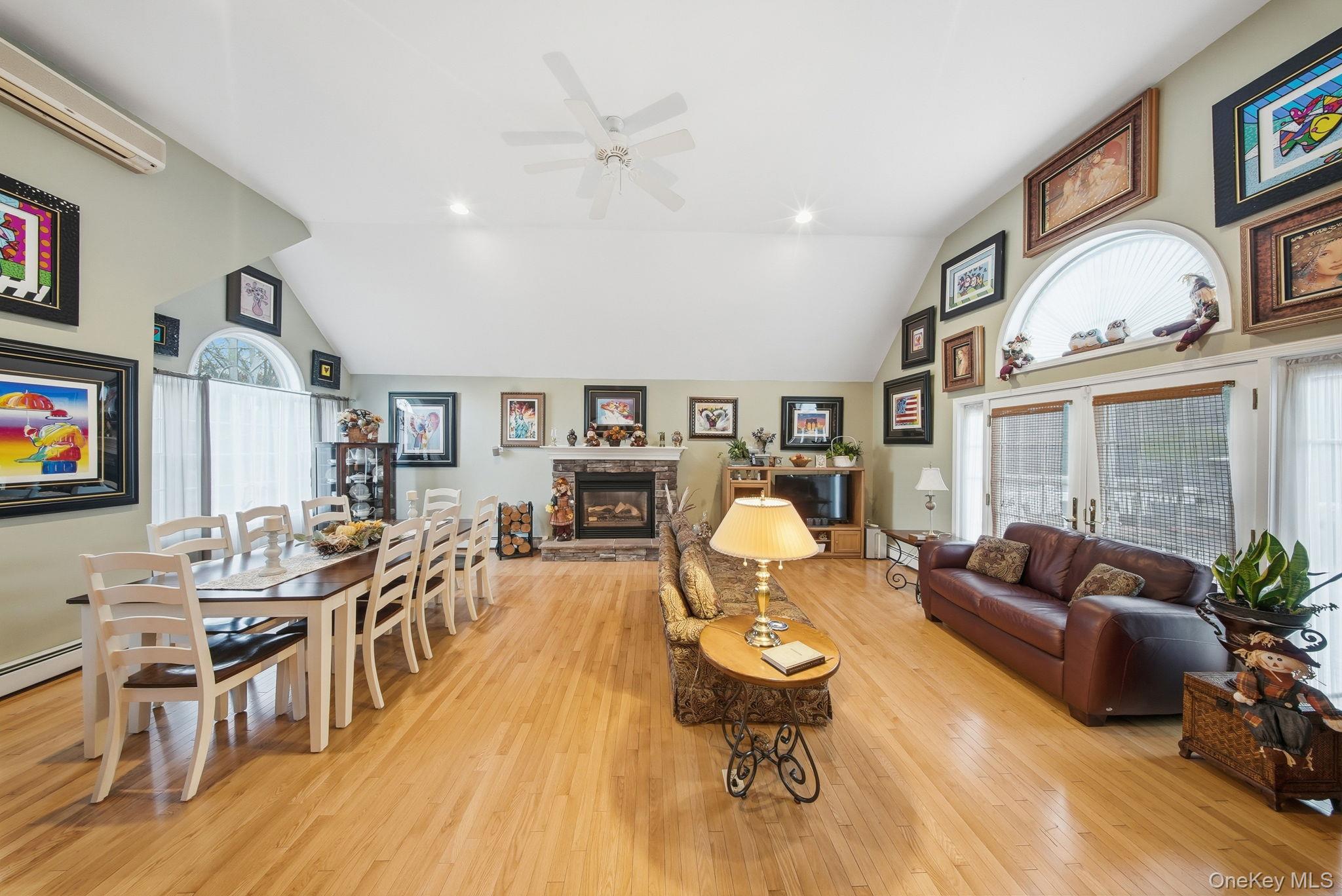 179 Reservoir Road Middletown, NY 10940 - Photo 11 of 50 Living room featuring a wall mounted AC, high vaulted ceiling, light wood-style floors, a stone fireplace, and ceiling fan