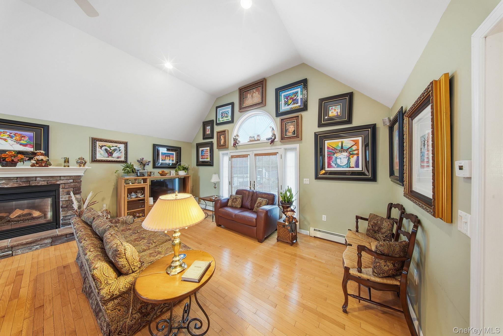 179 Reservoir Road Middletown, NY 10940 - Photo 12 of 50 Living room featuring light wood finished floors, a baseboard heating unit, a fireplace, and high vaulted ceiling