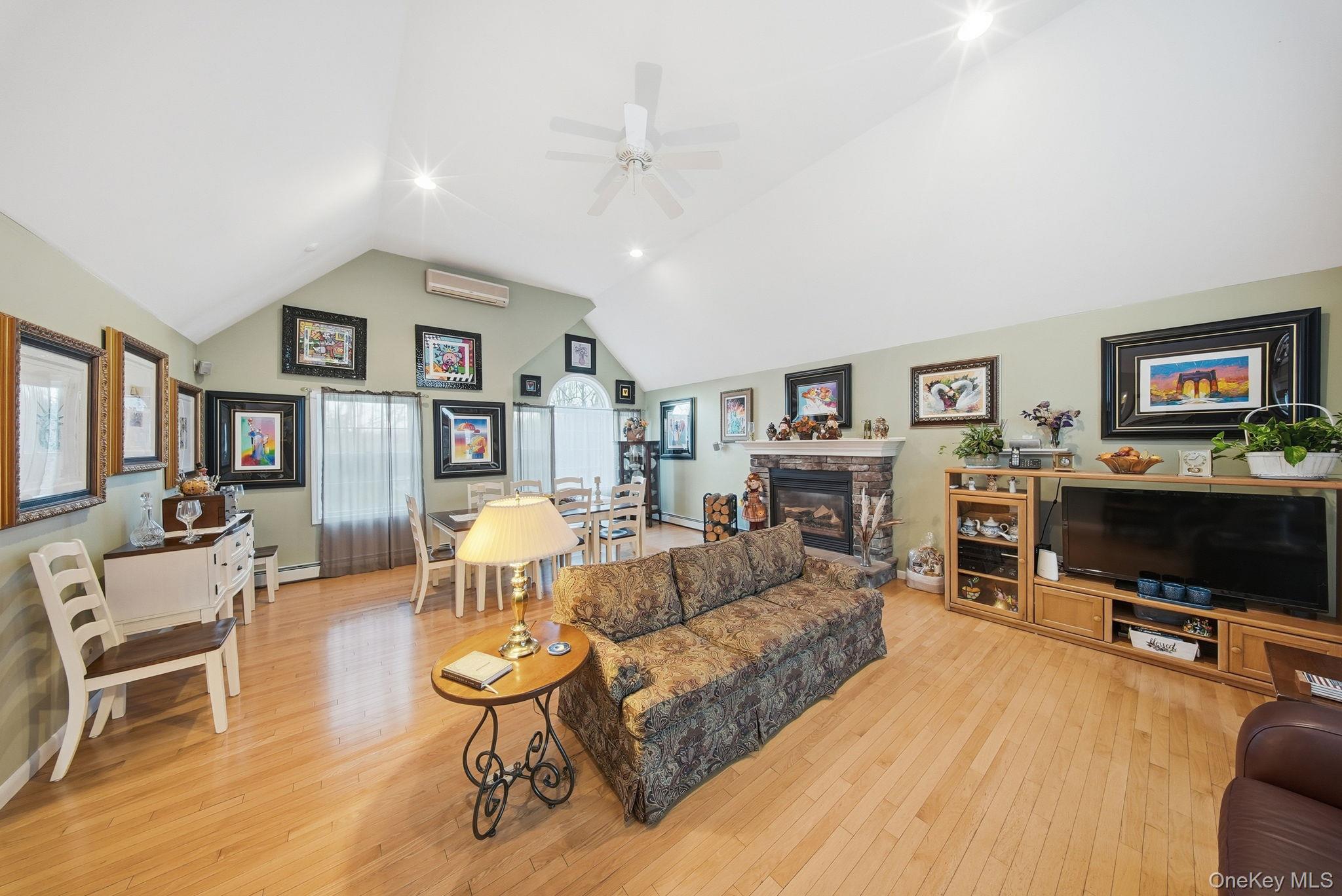 179 Reservoir Road Middletown, NY 10940 - Photo 13 of 50 Living room with light wood-style flooring, a wall mounted AC, a stone fireplace, high vaulted ceiling, and a ceiling fan