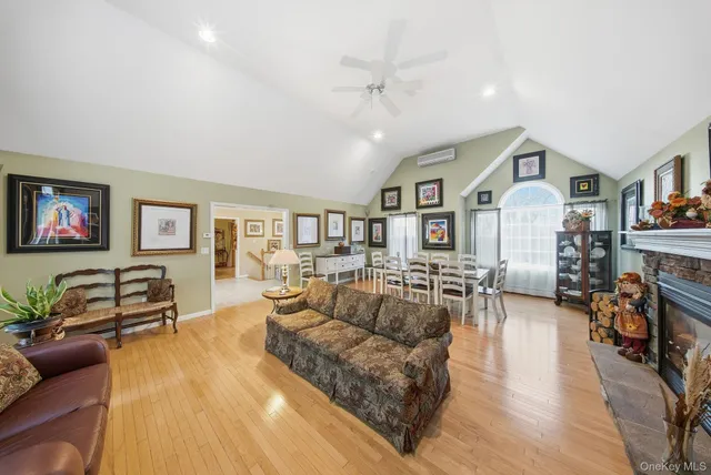 a living room with furniture two large window and wooden floor