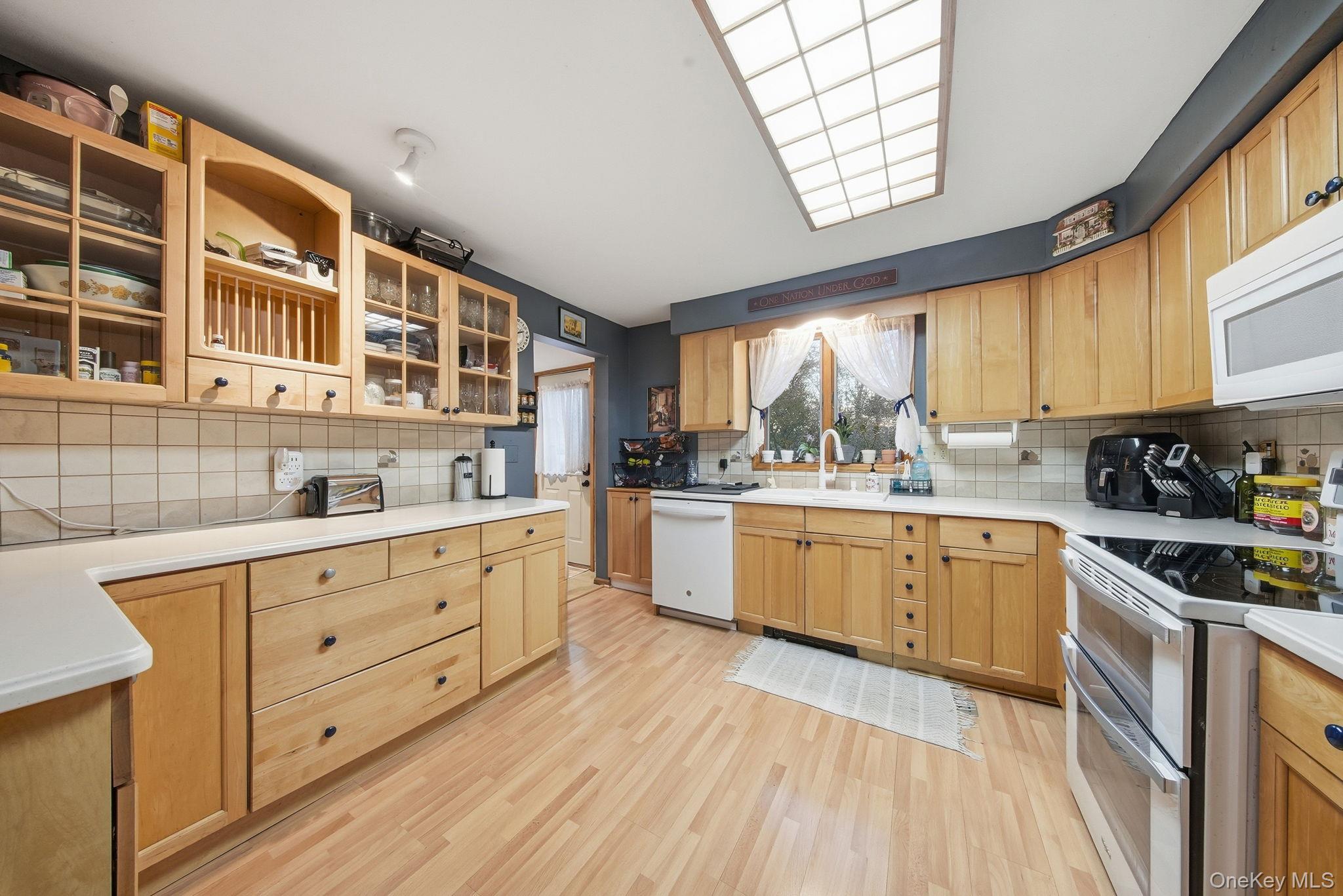 179 Reservoir Road Middletown, NY 10940 - Photo 21 of 50 Kitchen with white appliances, light countertops, glass insert cabinets, light wood-style flooring, and tasteful backsplash