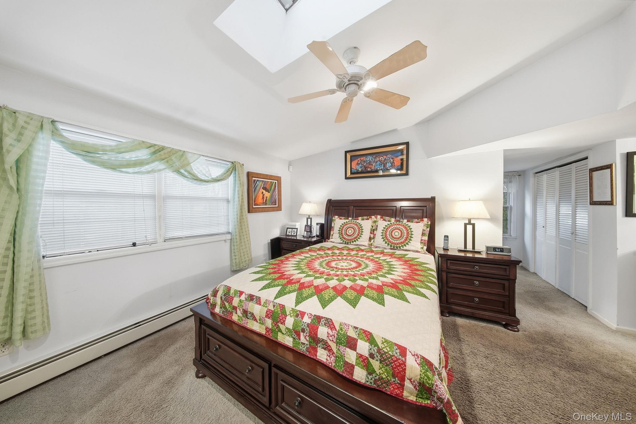 179 Reservoir Road Middletown, NY 10940 - Photo 28 of 50 Bedroom featuring a baseboard heating unit, light colored carpet, vaulted ceiling, a skylight, and a ceiling fan