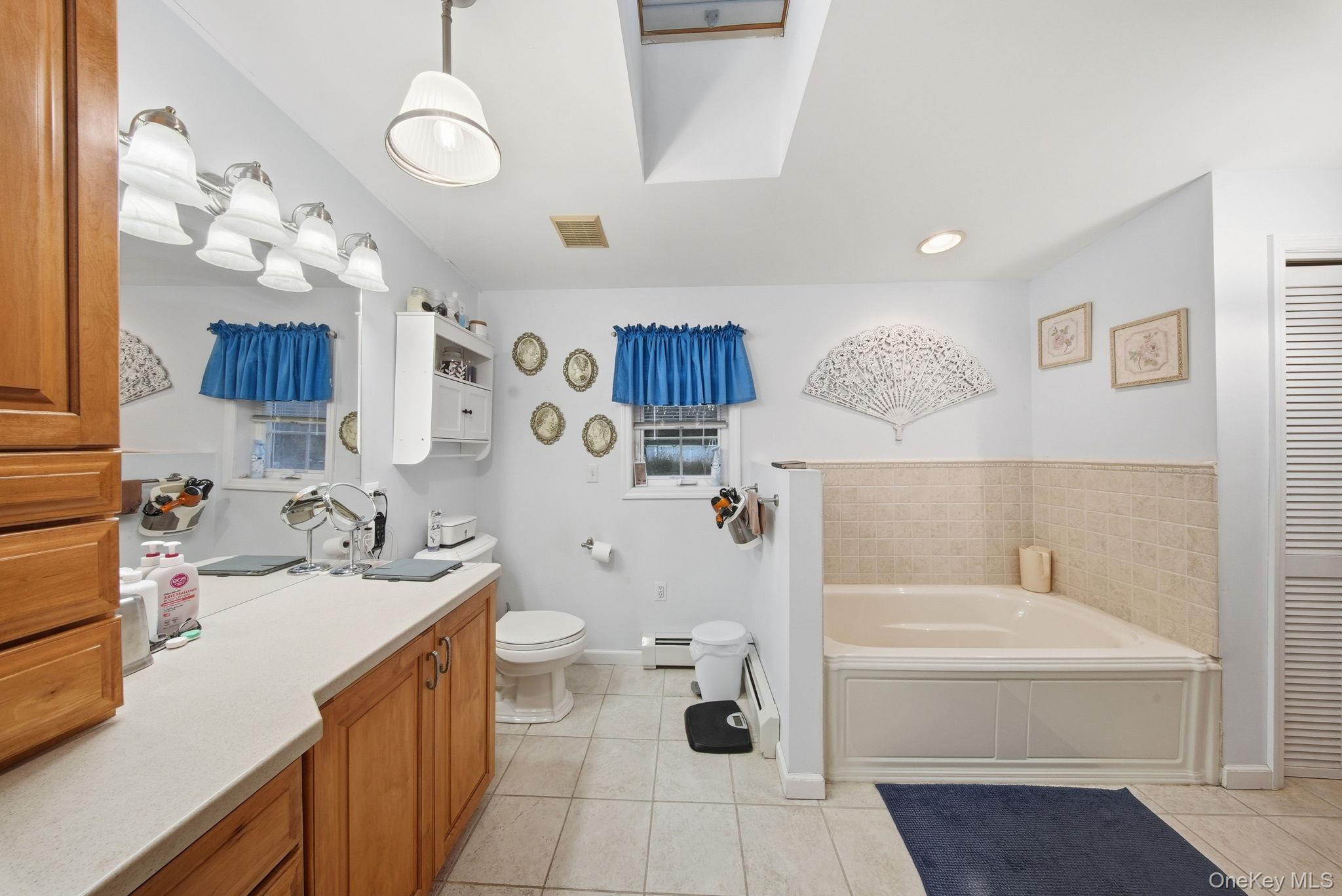 179 Reservoir Road Middletown, NY 10940 - Photo 33 of 50 Bathroom with a bath, light tile patterned flooring, a skylight, a baseboard heating unit, and vanity