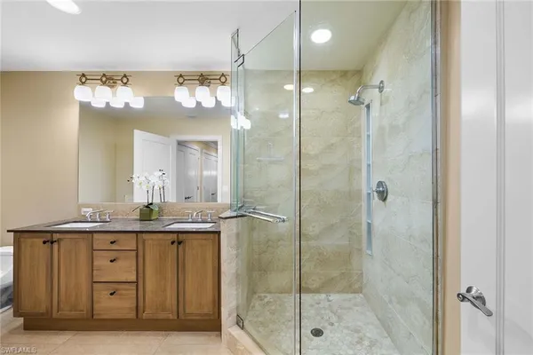a bathroom with a granite countertop sink a mirror and a shower