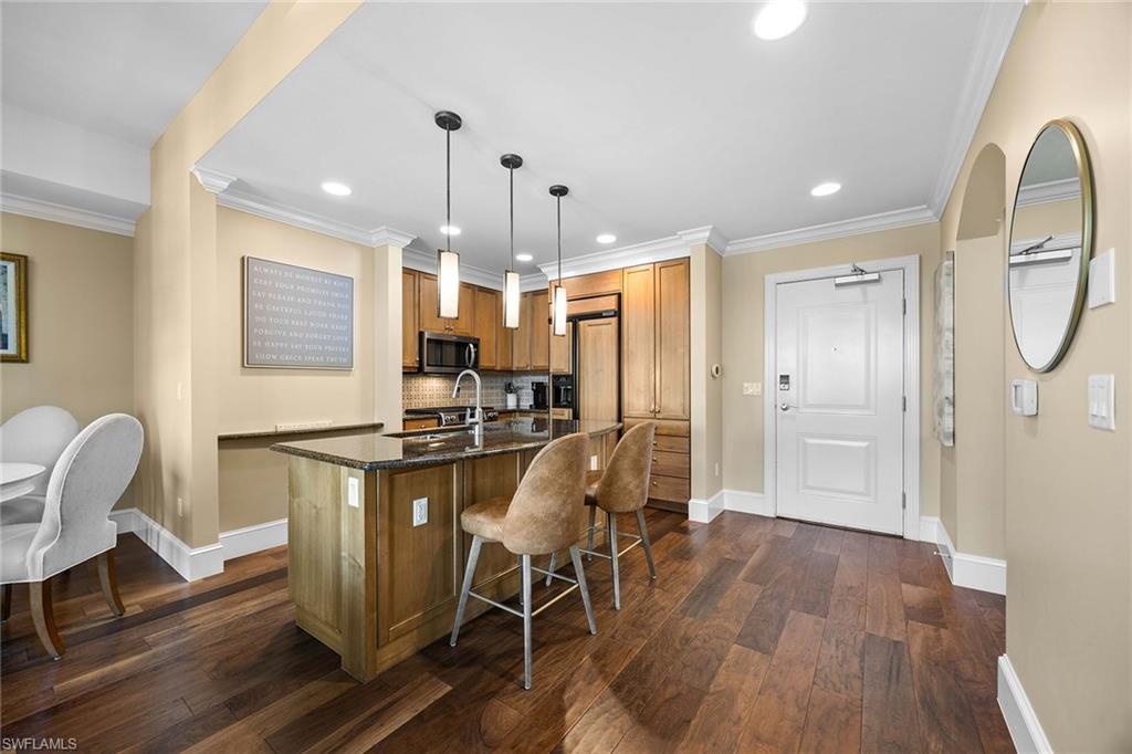 9123 Strada Place, Unit 7501 Naples, FL 34108 - Photo 3 of 28 a kitchen with stainless steel appliances a refrigerator a stove a sink dishwasher and a dining table with wooden floor