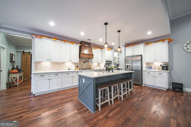 a kitchen with kitchen island a center island a counter space a sink appliances and cabinets