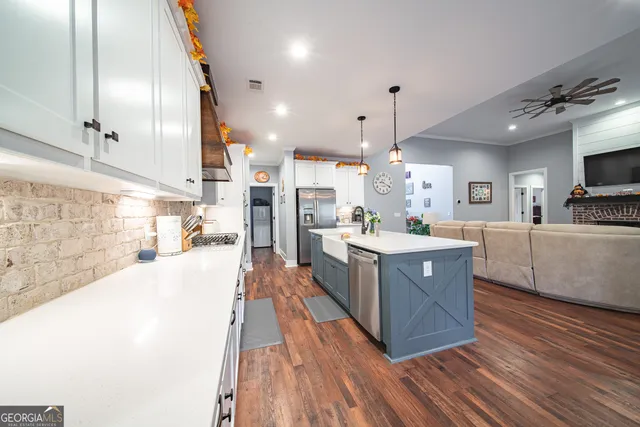 a kitchen with kitchen island a large counter top space a sink stainless steel appliances and cabinets