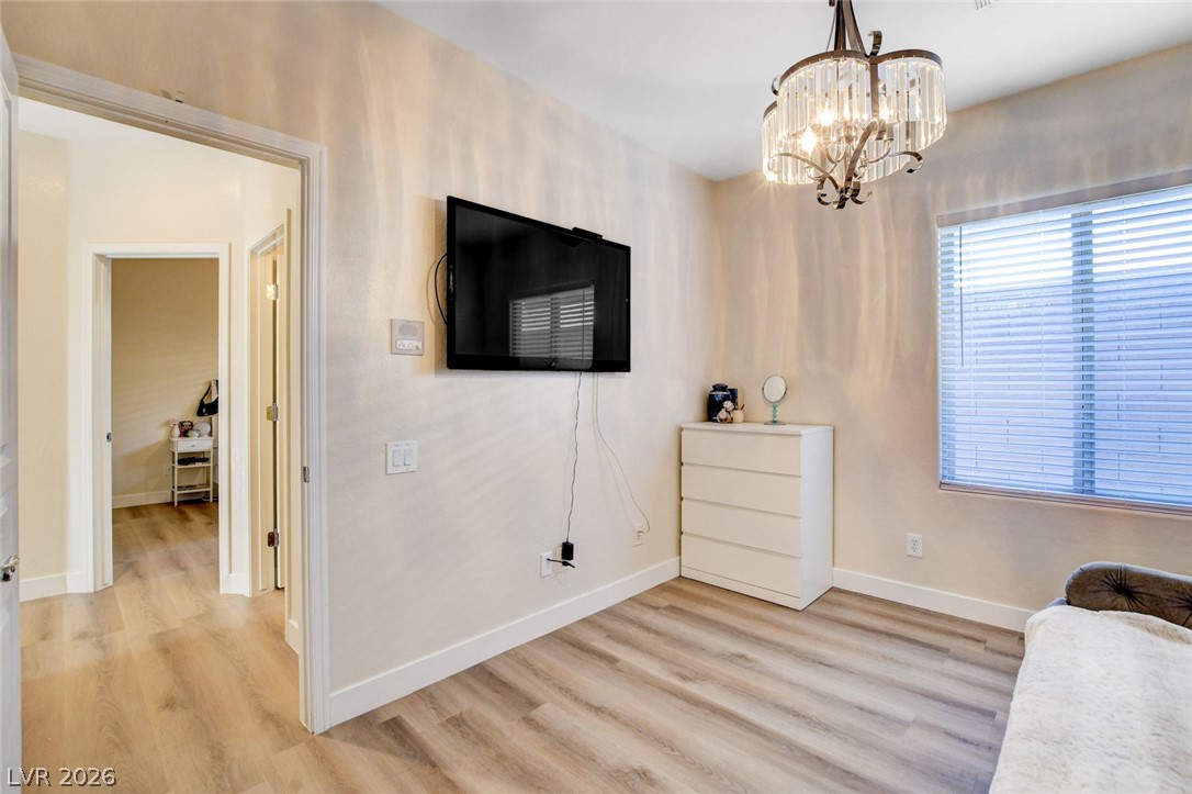 2649 Rue Marquette Avenue Henderson, NV 89044 - Photo 39 of 55 This cozy bedroom features durable wood flooring and a classic chandelier, offering a comfortable and stylish retreat.