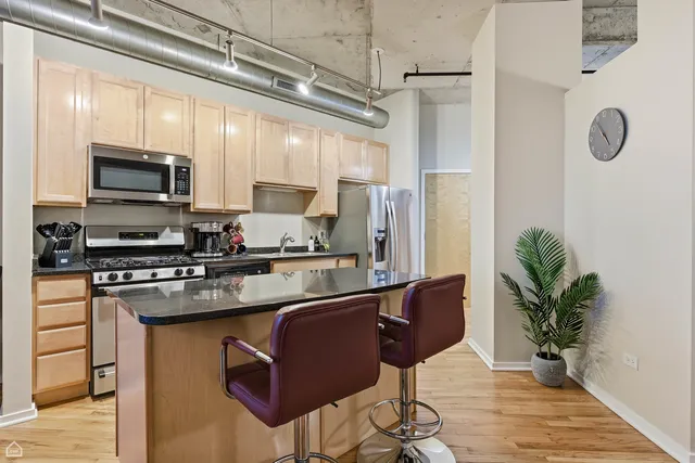 a kitchen with stainless steel appliances granite countertop a refrigerator a stove a sink dishwasher and white cabinets with wooden floor