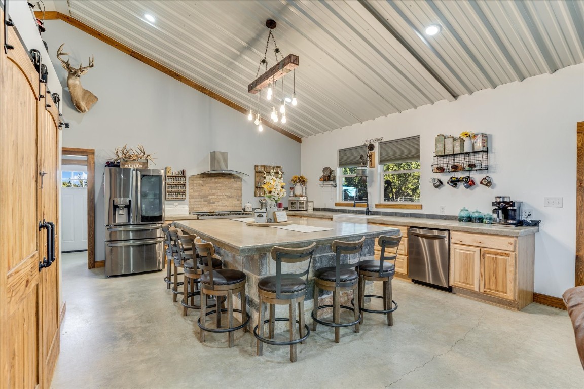 5450 County Road 202 Lampasas, TX 76550 - Photo 8 of 35 Kitchen with stainless steel fridge with ice dispenser, a barn door, decorative light fixtures, light brown cabinetry, and a kitchen island