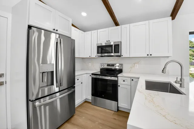a kitchen with stainless steel appliances a refrigerator sink and white cabinets