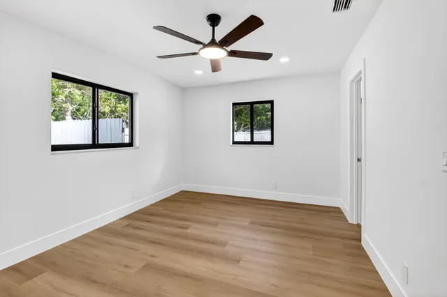 an empty room with wooden floor and windows
