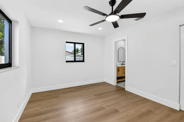 a view of empty room with wooden floor and fan