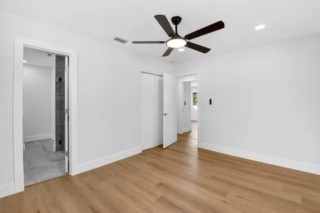an empty room with wooden floor and a ceiling fan