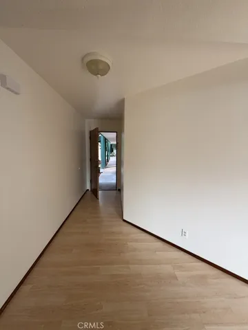 a view of an empty room with wooden floor and windows