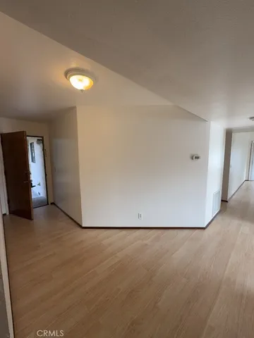 an empty room with wooden floor and entrance