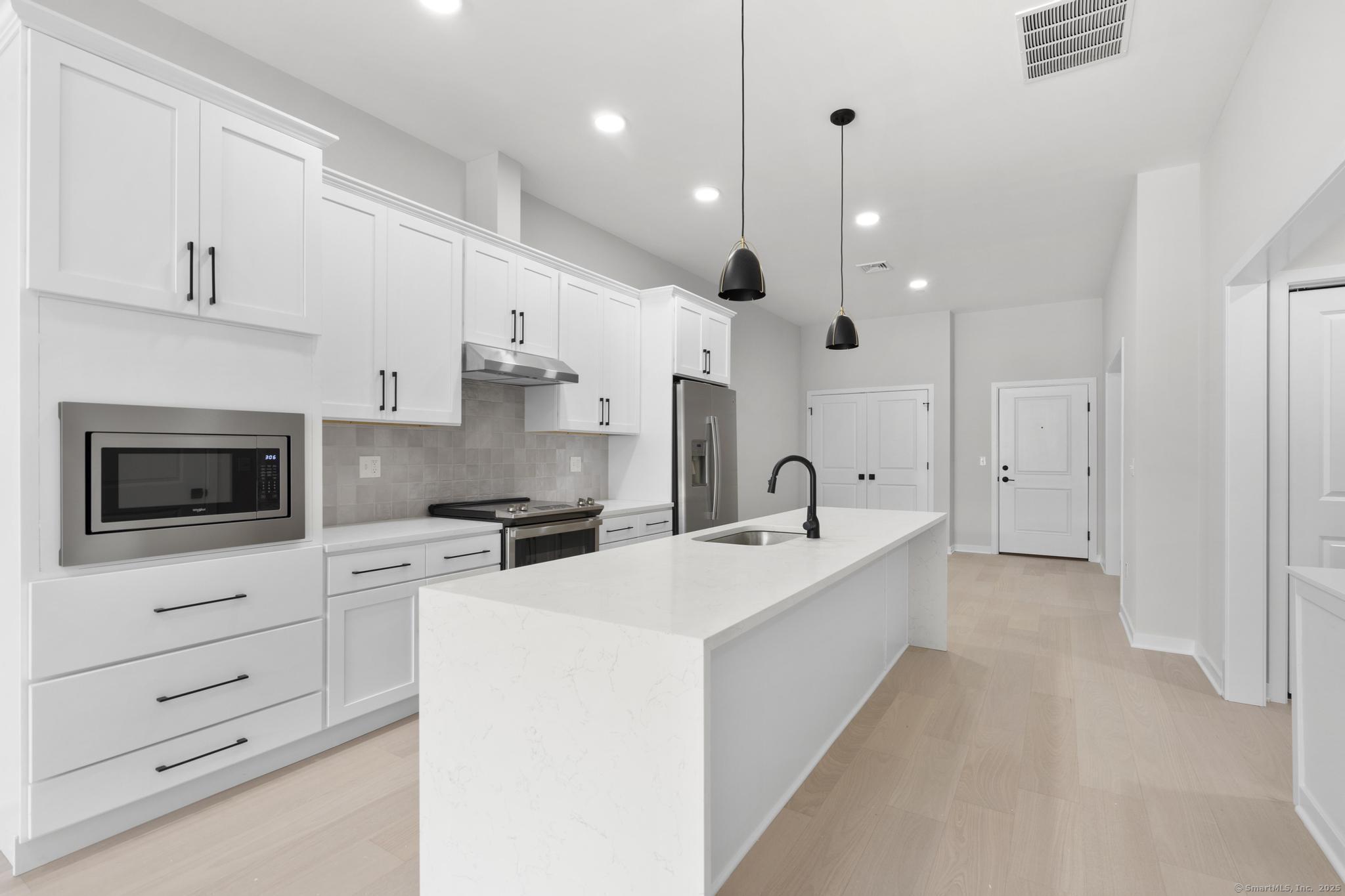 9 John Street Clinton, CT 06413 - Photo 11 of 18 a large kitchen with stainless steel appliances kitchen island granite countertop a sink a stove and a refrigerator