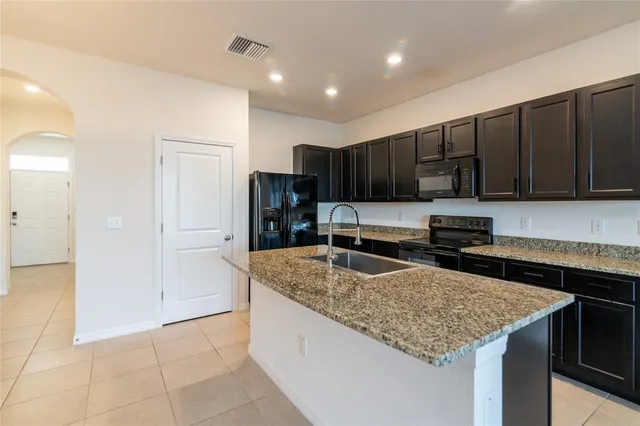 a kitchen with granite countertop stainless steel appliances a sink stove top oven and cabinets