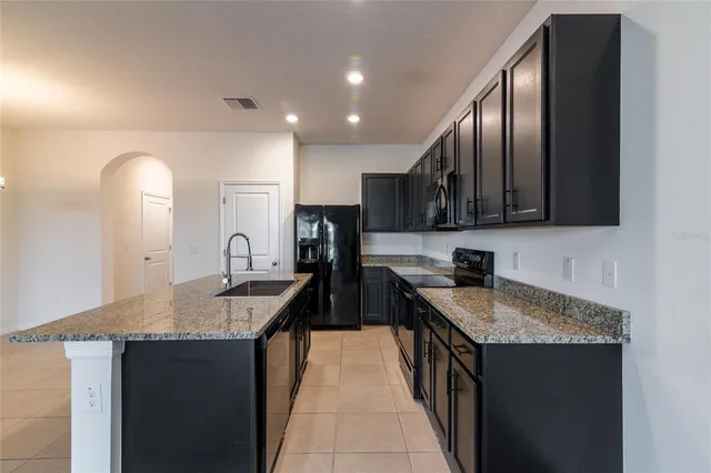 a kitchen with granite countertop kitchen island stainless steel appliances a sink stove and refrigerator