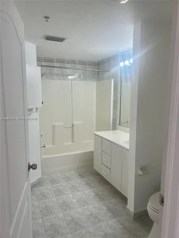 a bathroom with a granite countertop sink a toilet and shower