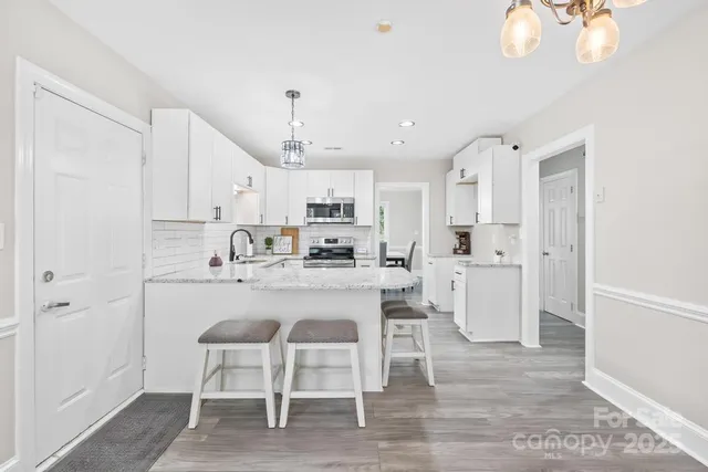 a kitchen with kitchen island a dining table chairs cabinets and stainless steel appliances