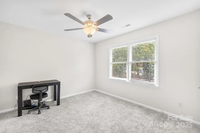 an empty room with a window and a ceiling fan