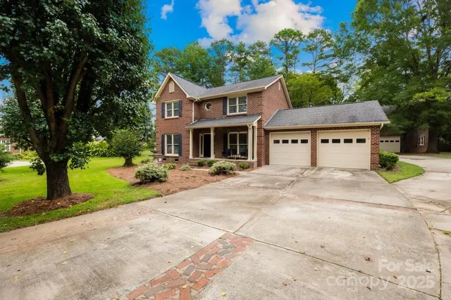 a view of a house with a yard and large tree