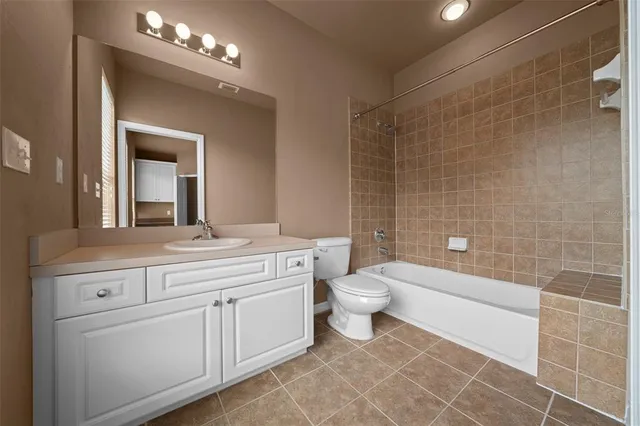 a bathroom with a toilet a sink a mirror a shower a vanity and window