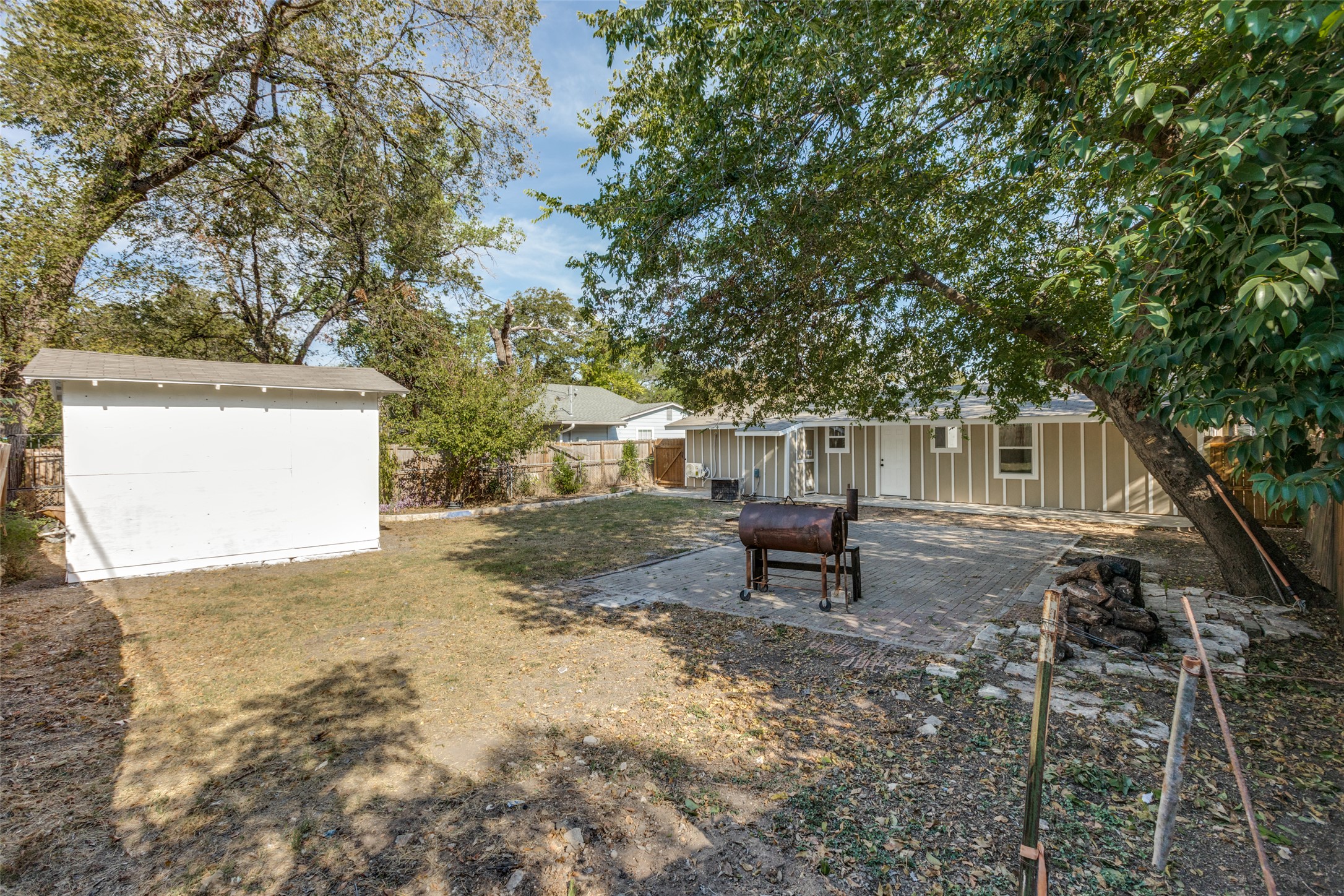 1118 Spur Street Austin, TX 78721 - Photo 15 of 21 A spacious backyard retreat, perfect for outdoor gatherings, features a shed, mature trees, and a brick paver patio.
