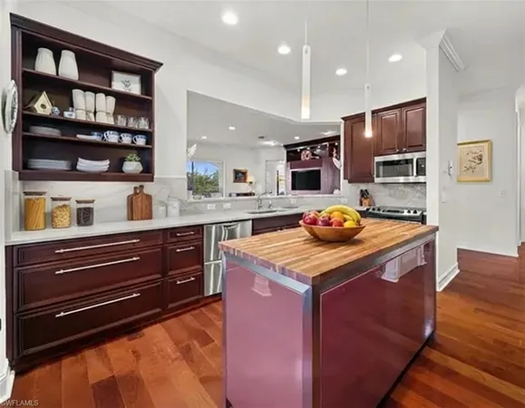 a kitchen with stainless steel appliances granite countertop wooden cabinets and a wooden floor