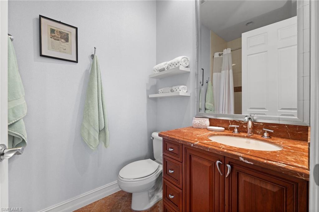 5045 Blauvelt Way, Unit 201 Naples, FL 34105 - Photo 32 of 39 a bathroom with a granite countertop sink toilet and mirror