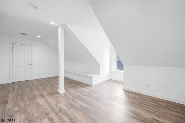 a view of an empty room with wooden floor and entryway