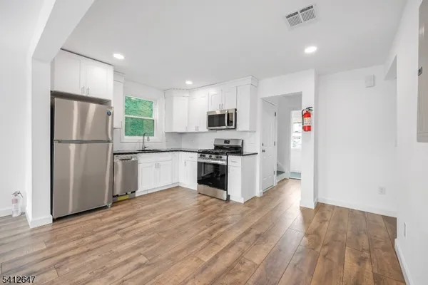 a kitchen with granite countertop a refrigerator and a stove top oven