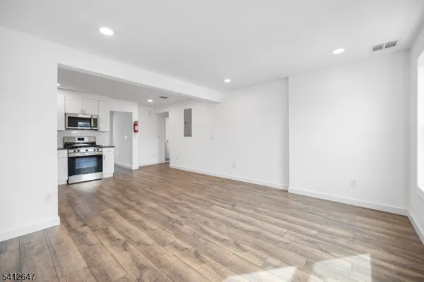 a view of kitchen and empty room with wooden floor