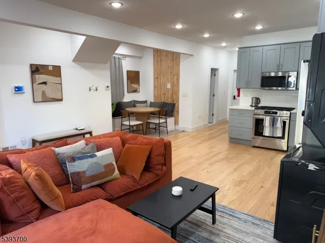 a living room with furniture kitchen and a wooden floor