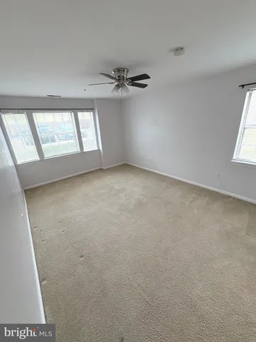 an empty room with windows and fan