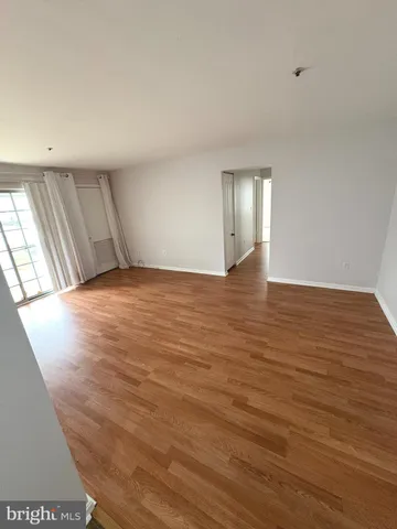 a view of an empty room with wooden floor and window