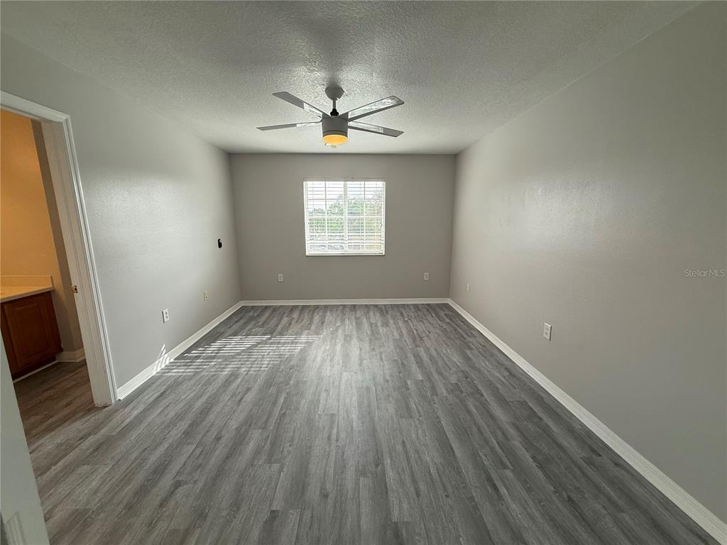 20460 Needletree Drive Tampa, FL 33647 - Photo 24 of 28 an empty room with wooden floor chandelier fan and windows