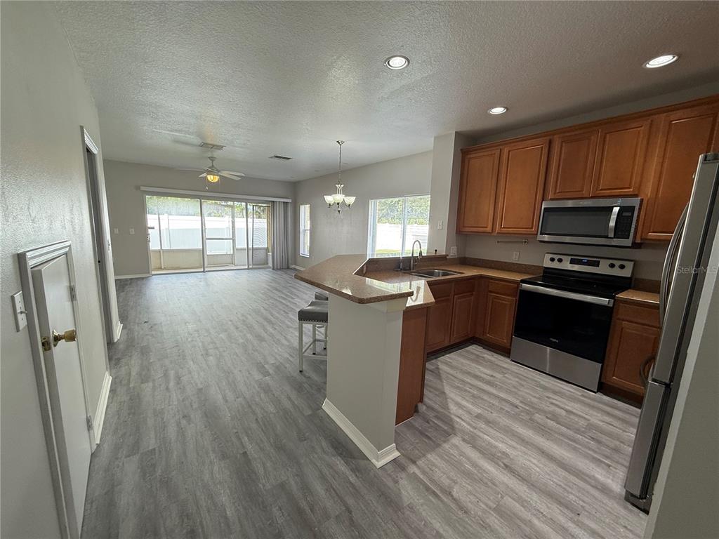 20460 Needletree Drive Tampa, FL 33647 - Photo 6 of 28 a kitchen with stainless steel appliances granite countertop a refrigerator a sink dishwasher a stove and white countertops with wooden floor