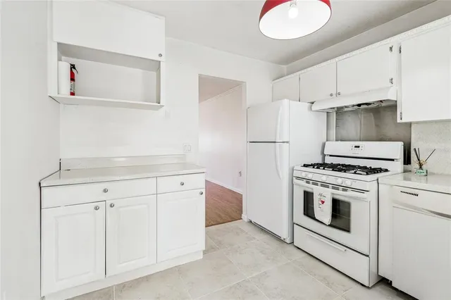 a kitchen with white cabinets and white appliances